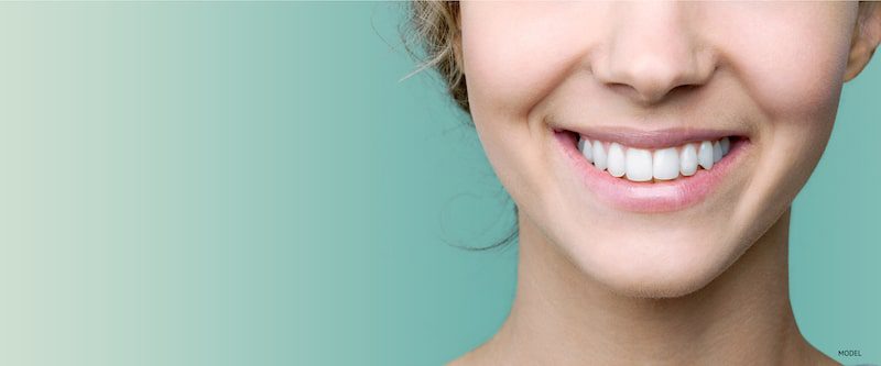 Close-up of woman's smiling against a mint green background.